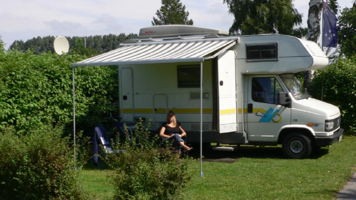 Frau sitzt vor einem Campingbus