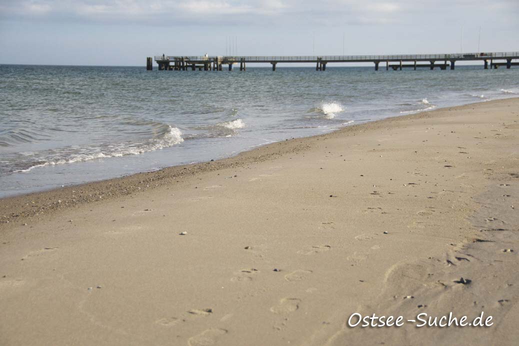 Ostseestrand in Dahme mit Seebrücke Sie sehen Laufspuren im Ostseesand, die Wellen der Ostsee und im Hintergrund die Seebrücke von Dahme