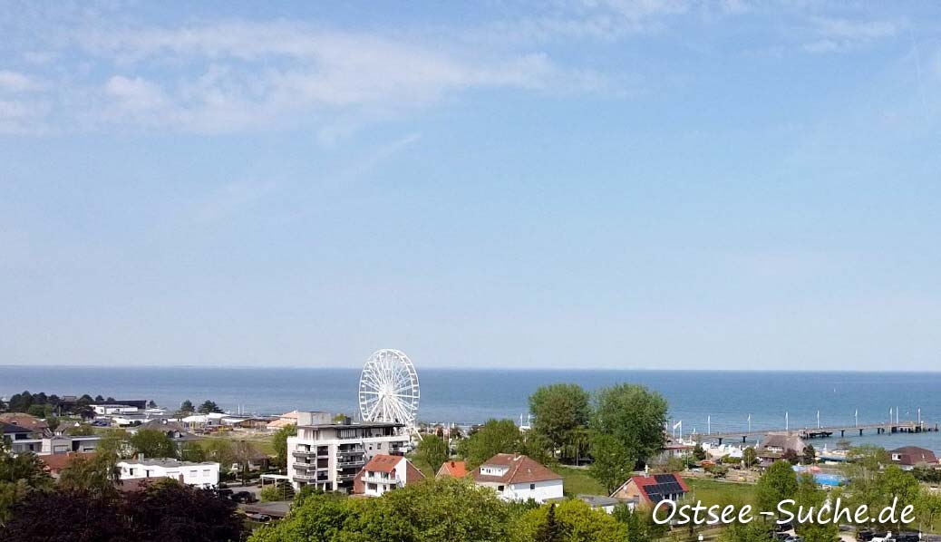 Dahme Ostsee Eine Luftaufnahme vom Ostseebad Dahme. An der Linken Seite steht ein Riesenrad, in der Mitte befindet sich die Seebrücke. Im gesamten Hintergrund ist die Ostsee zu sehen.