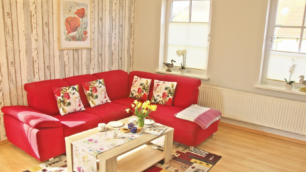 Wohnzimmer mit rotem Sofa in der Ferienwohnung Mohn