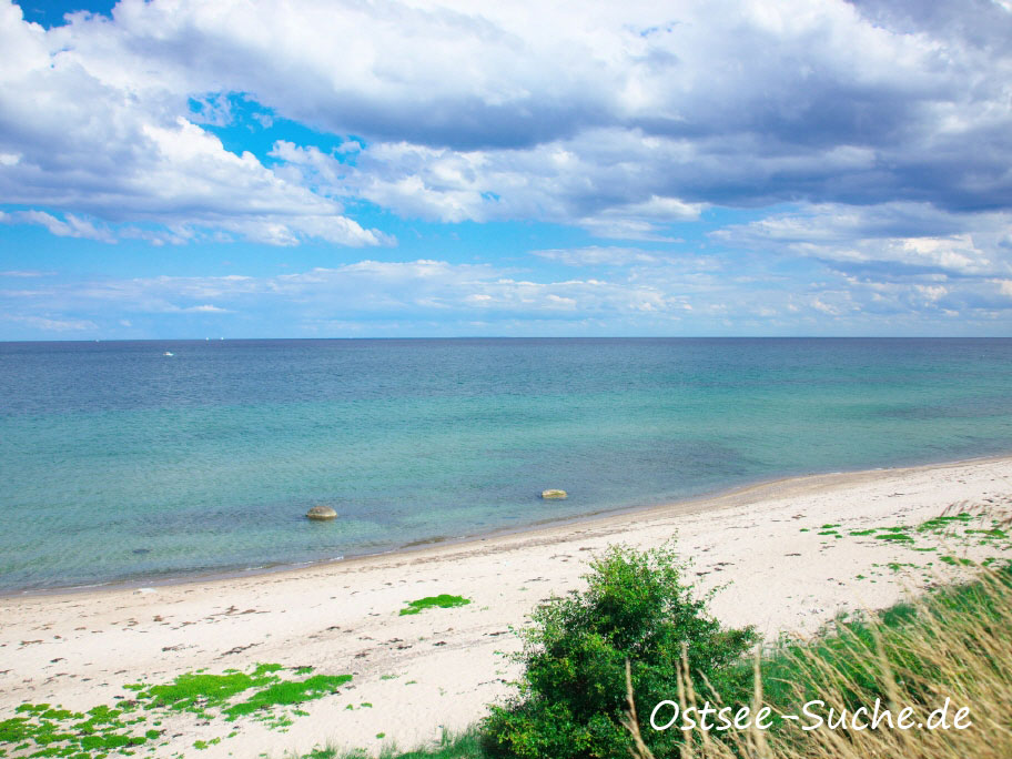 Der Kraksdorfer Strand, es ist windstill und auf der Ostsee sind keine Wellen zu sehen. Zwei Findlingsteine ragen aus der Ostsee heraus.