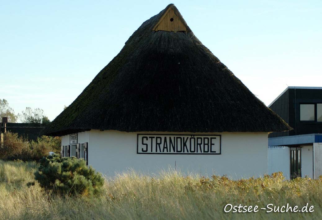 Strandkorbvermietung Dahme Ein Reetdachhaus an der Strandpromenade von Dahme mit der Werbeaufschrift Strandkorbvermietung